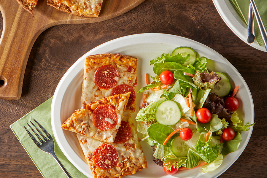 Pizza and salad on an EcoSave plate on a table