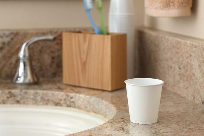 Small white bathroom cup sitting on bathroom counter.