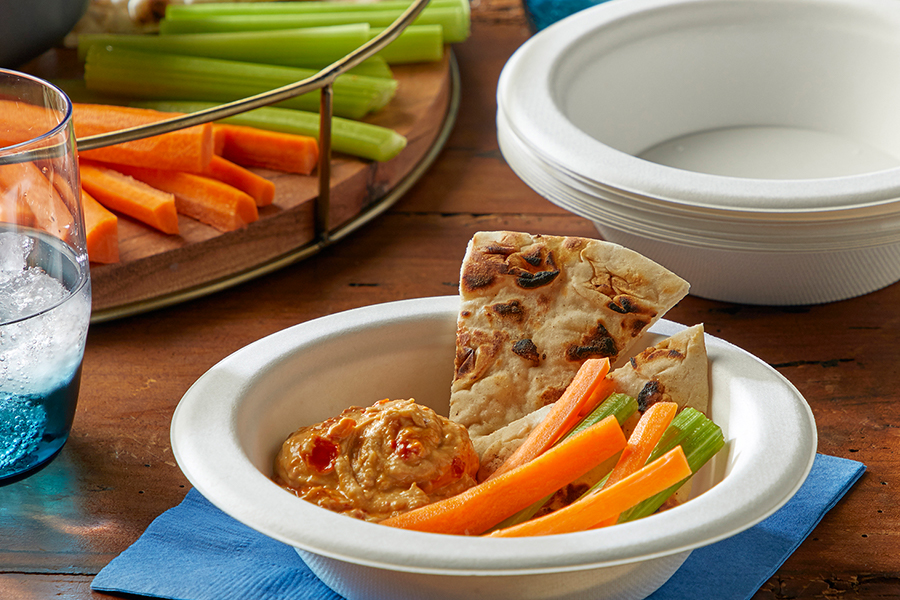 Hummus, pita chips and vegetables in an EcoSave bowl on a table