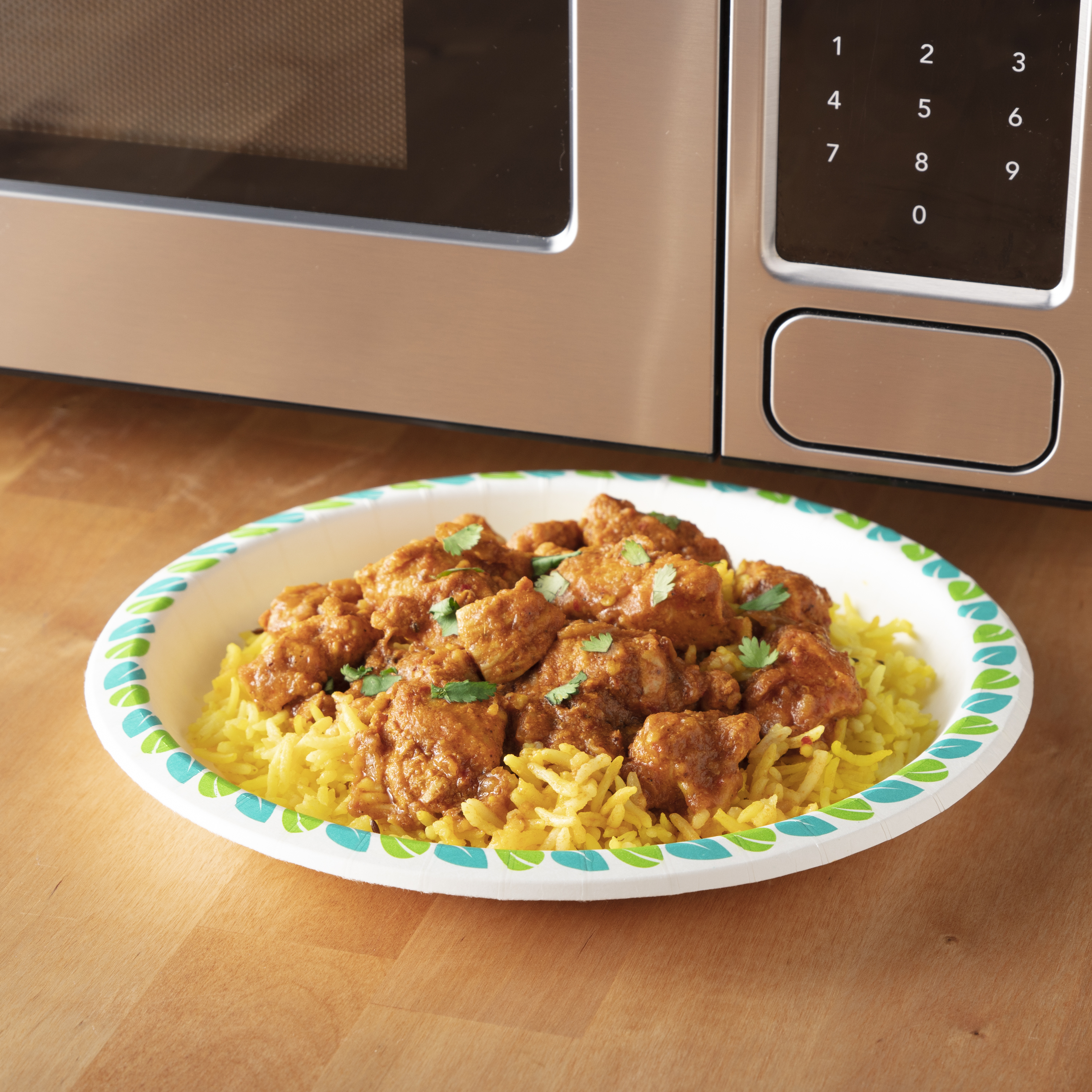 paper plate topped with chicken and rice sitting in front of a microwave