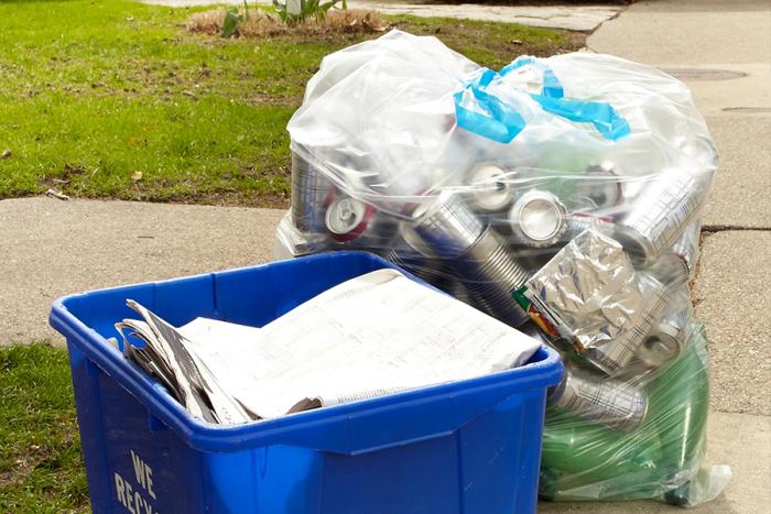 Clear recycling bag set at the curb with a recycling bin.