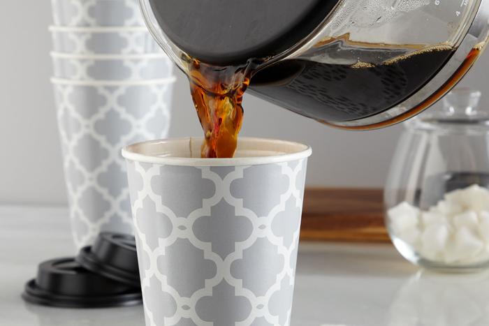 Coffee being poured into an insulated hot beverage cup on counter