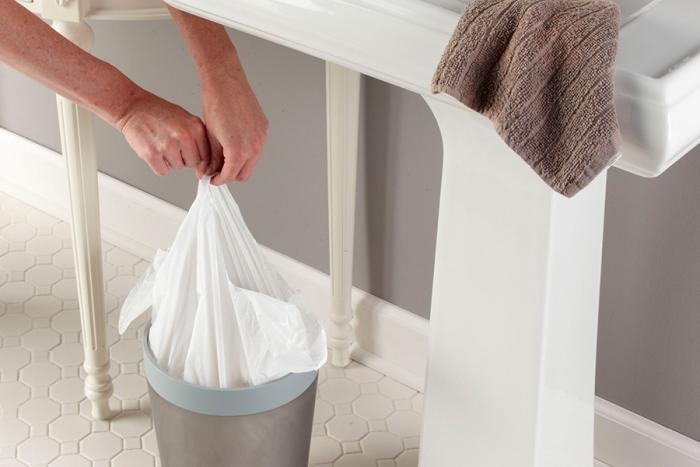 Person tying up a small trash bag.