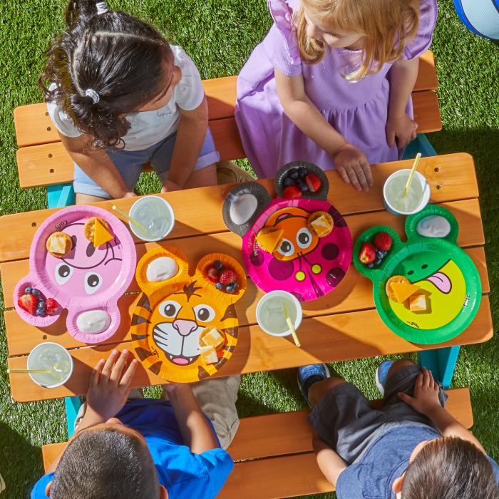 Children sitting at a picnic table eating sliders and french fries off of Zoo Pal plates