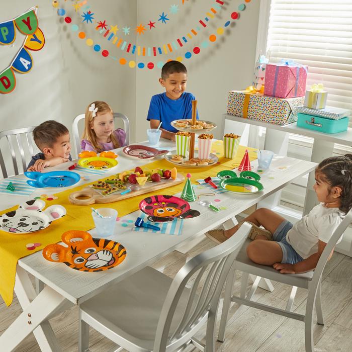 Children at a birthday party sitting at a table with Zoo Pals plates and fun finger food