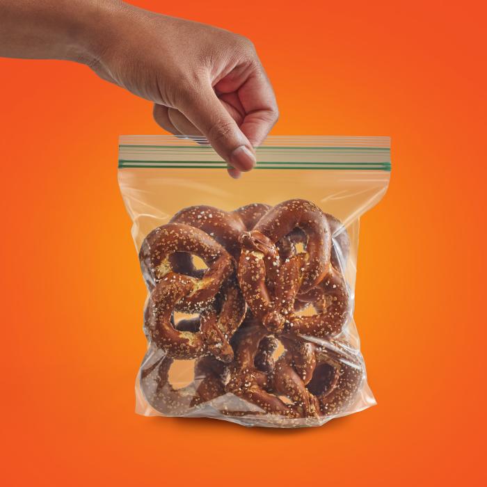 Person sealing a sandwich XL sized Hefty Press to Close storage bag filled with pretzels