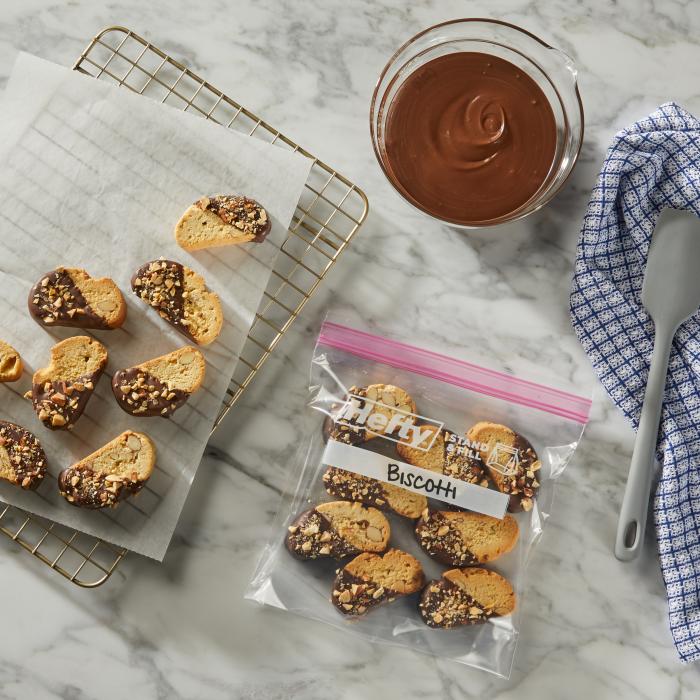 Biscotti dipped in chocolate sitting in a sealed quart sized Hefty Press to Close bag on a kitchen counter