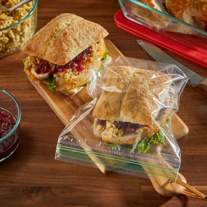 Turkey sandwich in a sealed Sandwich XL sized Hefty Press to Close storage bag surrounded by Thanksgiving leftovers