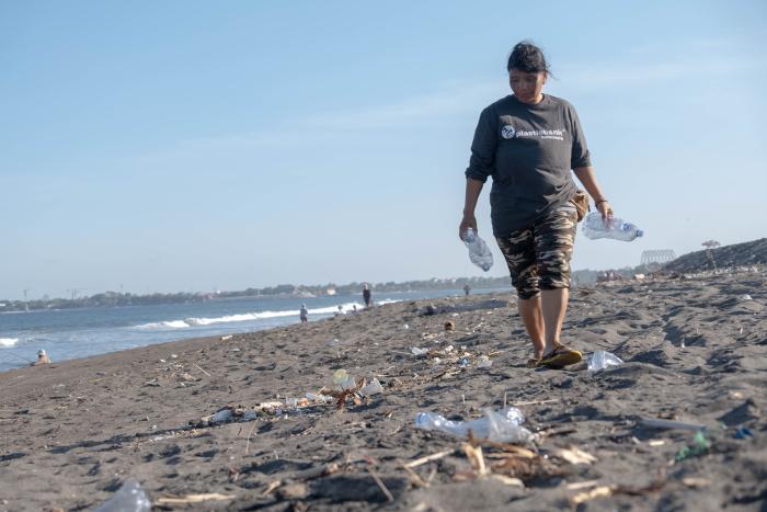 Women walking on the beach holding plastic bottles