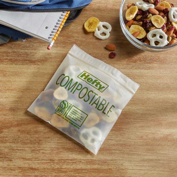 Trail mix in a Hefty compostable press to close storage bag sitting alongside a backpack and notebook