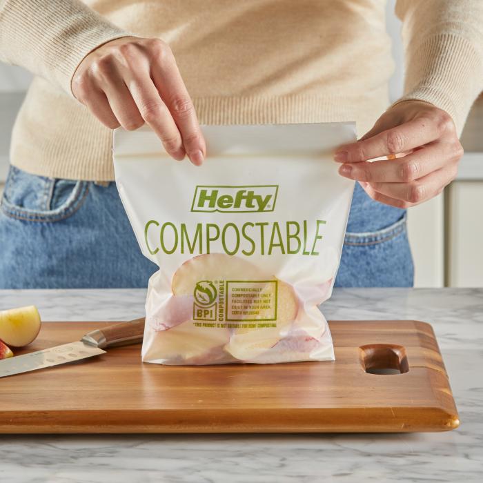 Person sealing a Hefty Compostable Press to Close Storage Bags filled with sliced apples