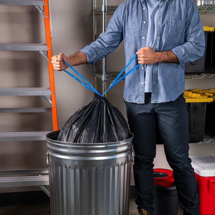 Person tying the drawstrings on a Hefty Ultra Strong large black bag