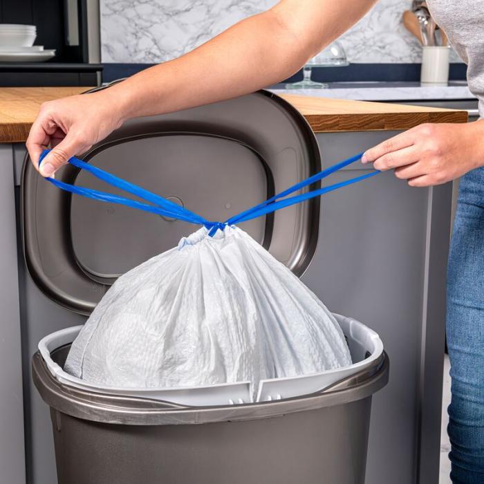 Person tying the drawstrings of a Hefty Ultra Strong Tall Kitchen Trash Bag