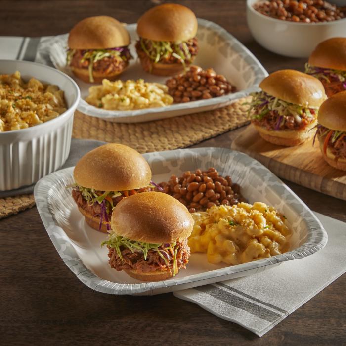 Two pulled pork sliders, baked beans and mac and cheese sitting on an Hefty Extra Deep paper plate