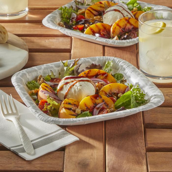 Outdoor table topped with two Hefty Extra Deep paper plates topped with a burrata salad