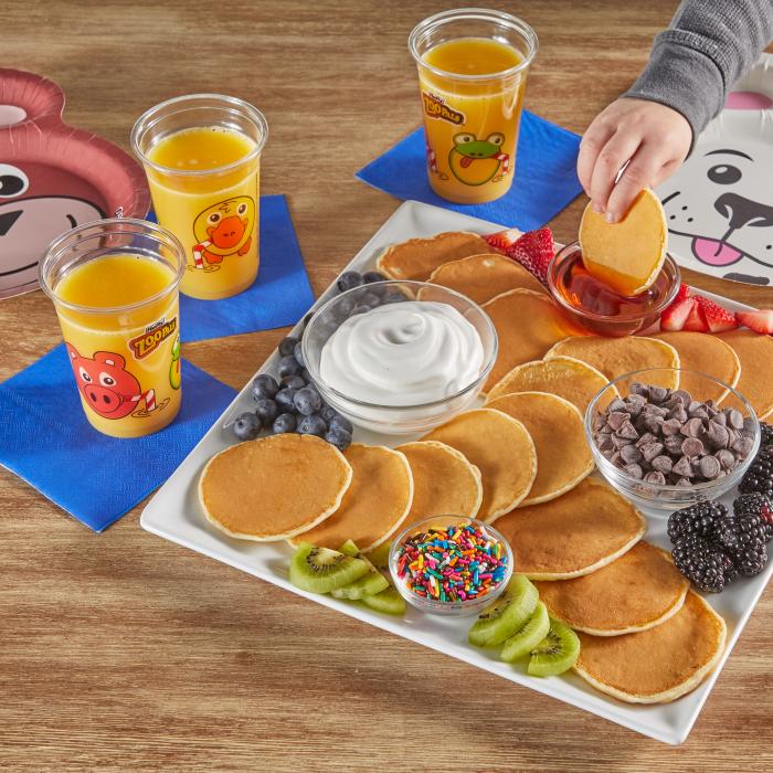 Plate of pancakes sitting on a table alongside Zoo Pals Cups