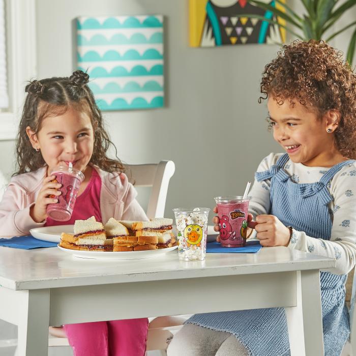 Two kids sitting at a table having a snack and fruit smoothie in a Zoo Pals Cup