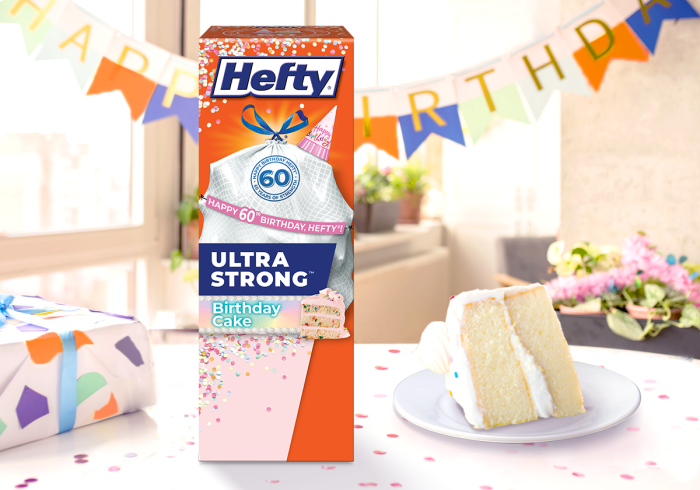 Hefty Ultra Strong birthday cake scented trash bag box sitting on a table alongside a slice of cake.