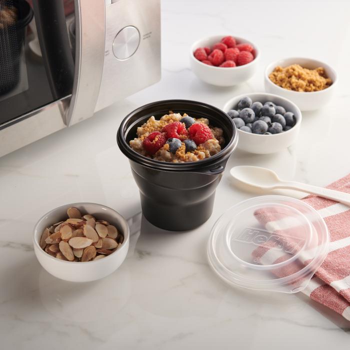 Hefty Multi-Purpose cup filled with oatmeal sitting in front of a microwave and surrounded by various toppings