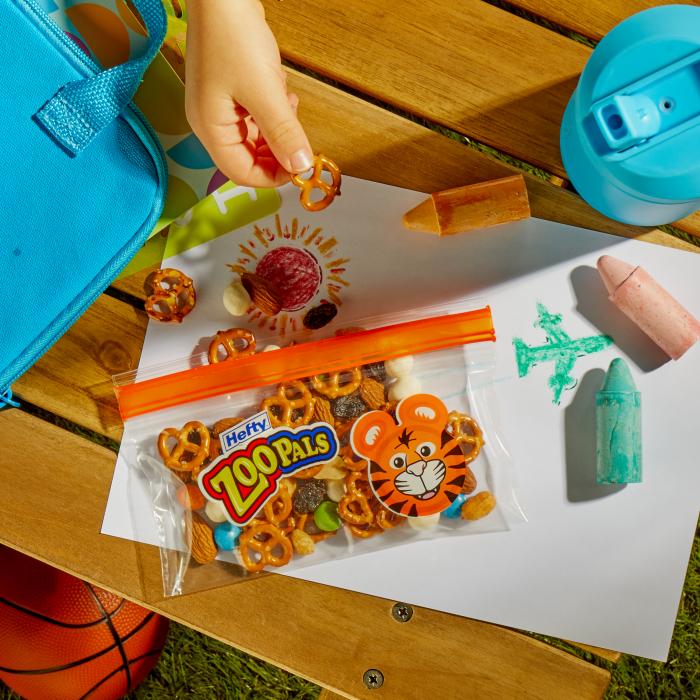 child removing a pretzel twist from a Hefty Zoo Pals snack size storage bag
