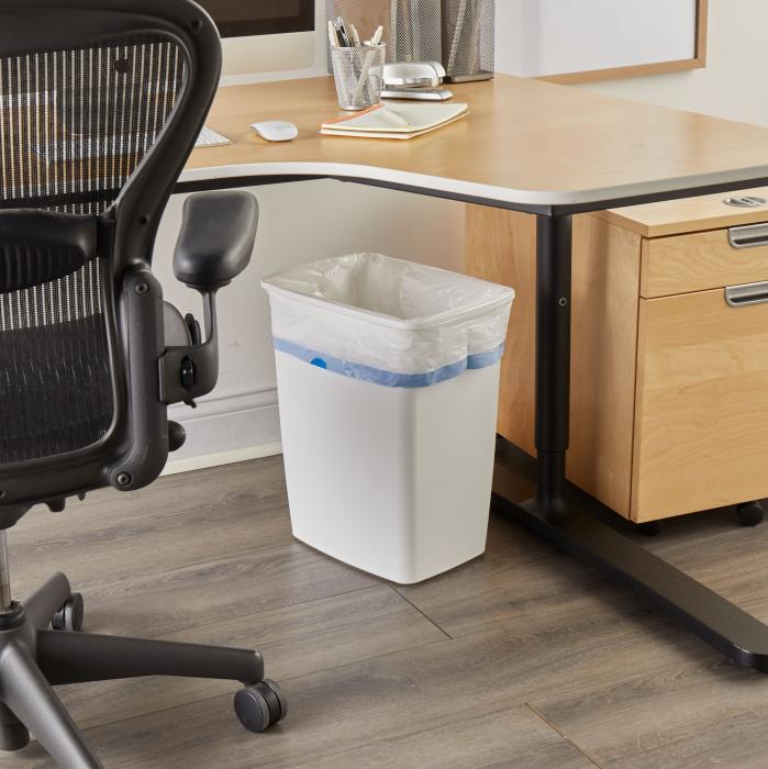 Medium trash bag in a white trash can sitting under an office desk