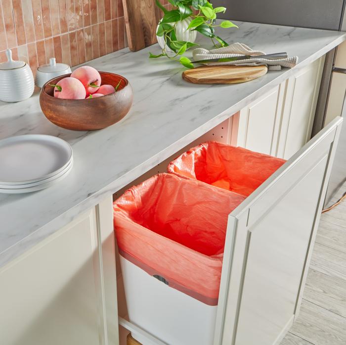 peach colored trash bags in a pull out trash can in a kitchen