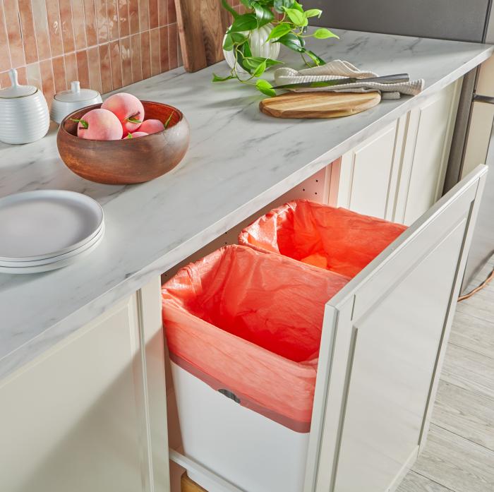 Kitchen with a drawer pulled out to reveal two peach colored trash bags