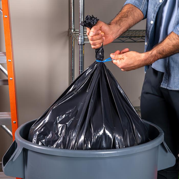 person tying a Hefty Contractor bag with a blue twist tie