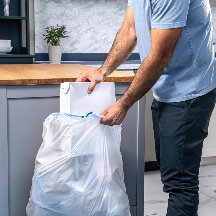 person stuffing a pizza box into a Hefty Strong 13 gallon tall kitchen trash bag