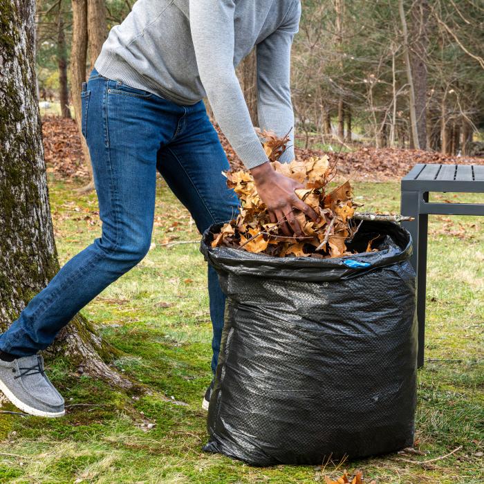 person stuffing leaves into a 39 gallon Hefty Ultra Strong Lawn and Leaf bag