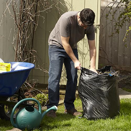 person stuffing yard waste into a 39 gallon Hefty Ultra Strong Lawn and Leaf bag