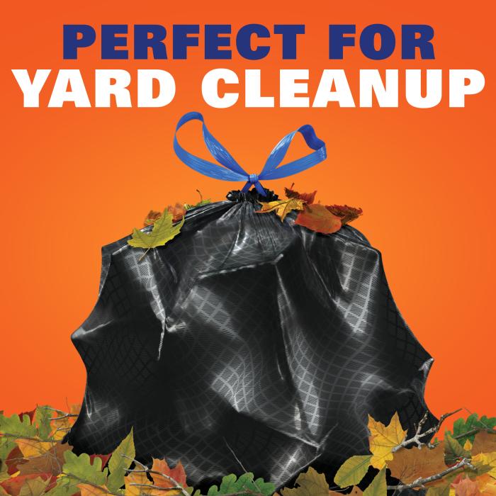 Stuffed black trash bag sitting in a pile of leaves