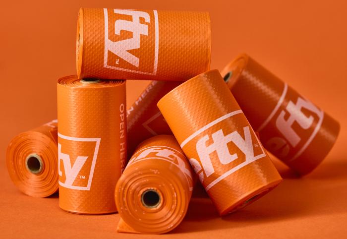 A pile of Hefty Dog Poop Bag rolls on an orange background